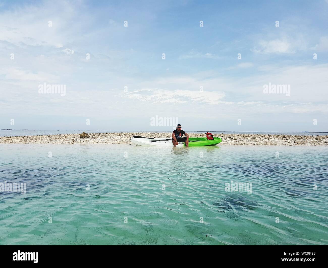 Man With Kayak At Beach Against Sky Stock Photo