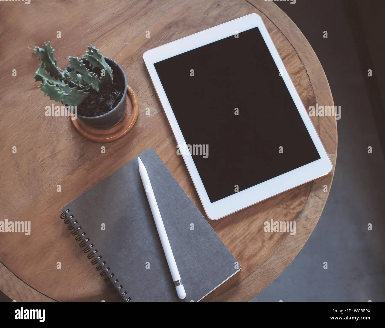 High Angle View Of Book And Digital Tablet By Houseplant On Table Stock Photo