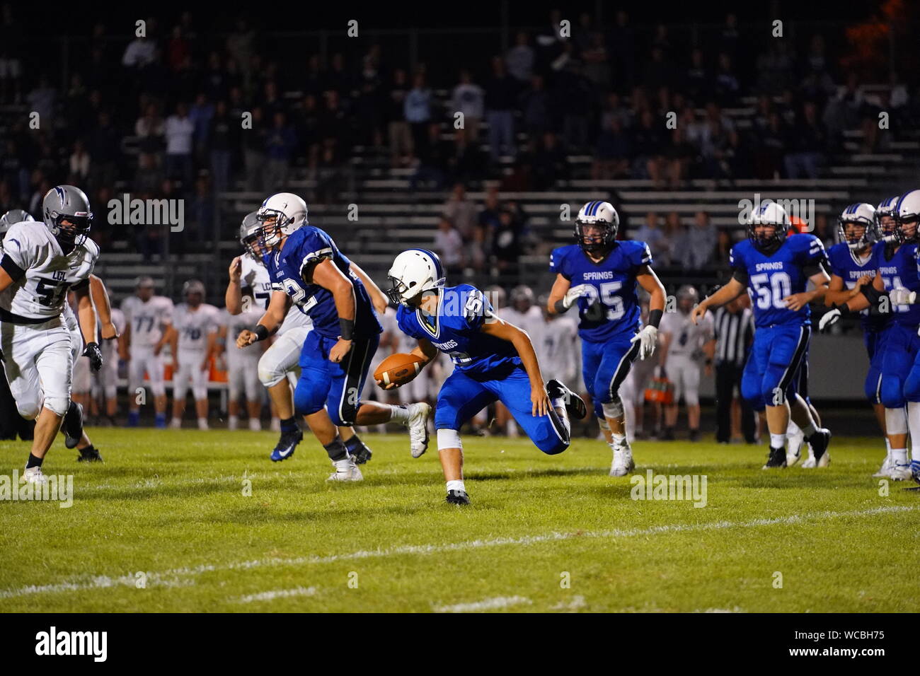 High School Football game played at night while many fans enjoy the