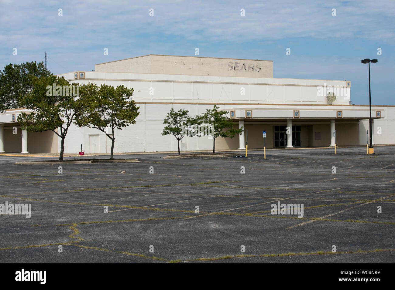 A faded outline of a logo sign outside of a closed and abandoned Sears
