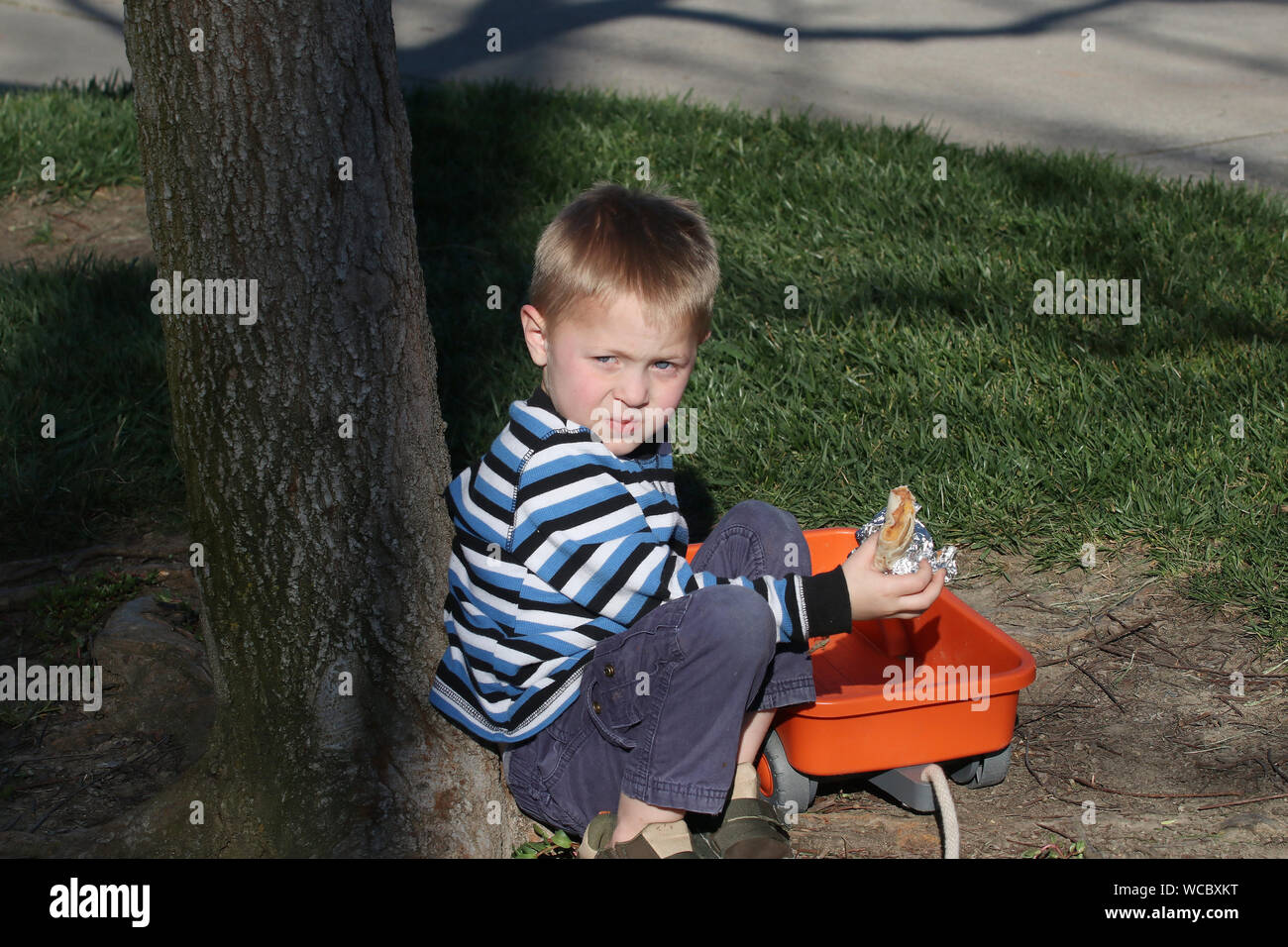 Young boy sneaking a burrito from the table hiding. Stock Photo