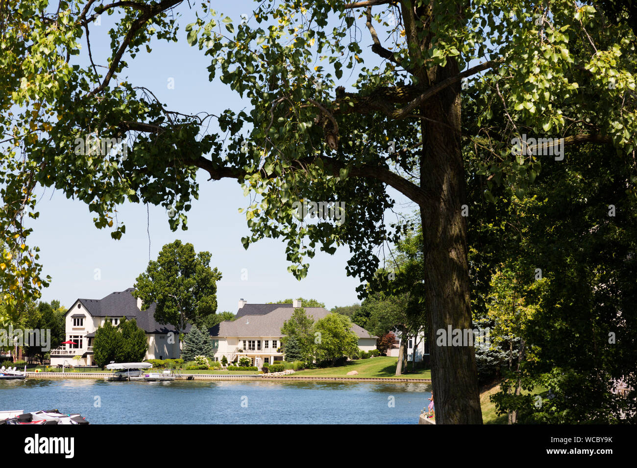 Suburban waterfront homes seen through the trees along Geist Lake in Hamilton County, Indiana, USA. Stock Photo