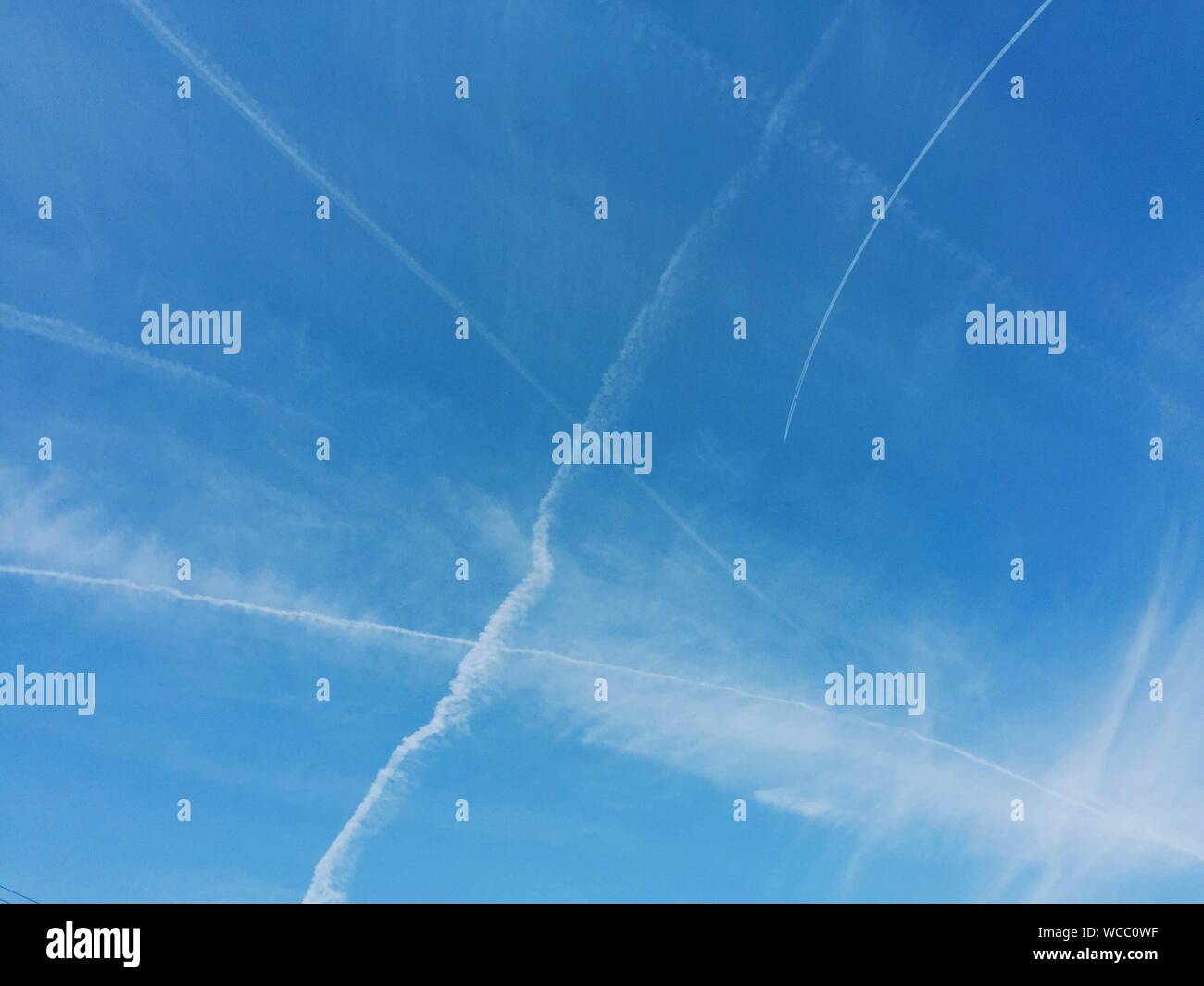 Low Angle View Of Vapor Trails Against Blue Sky Stock Photo