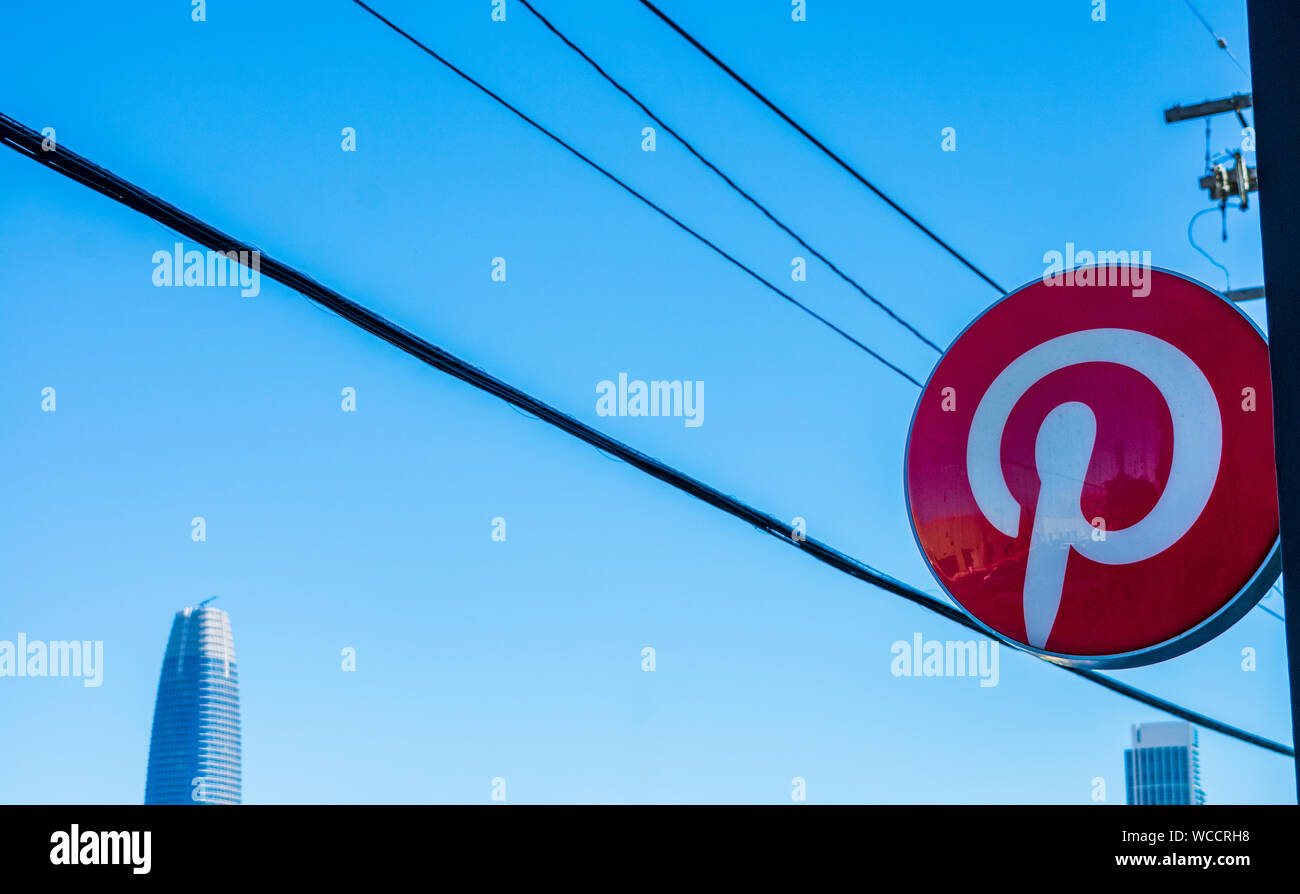 Pinterest logo on facade of social media startup headquarters with blurred electrical overhead wires, downtown skyline and blue sky Stock Photo
