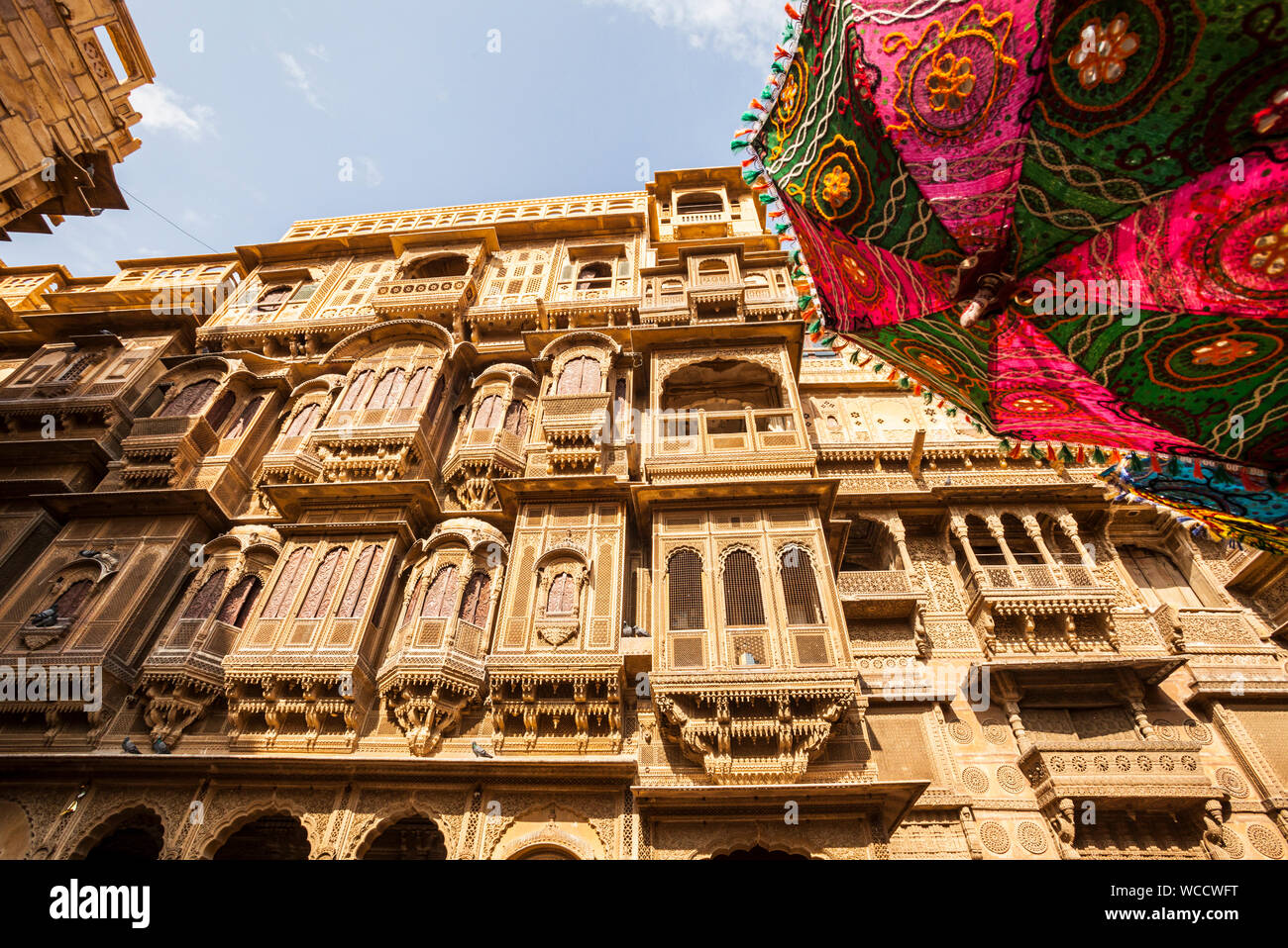 One of the many amazing Havelis in Jaisalmer, Rajasthan, India and a parasol adorned with decorations. Stock Photo