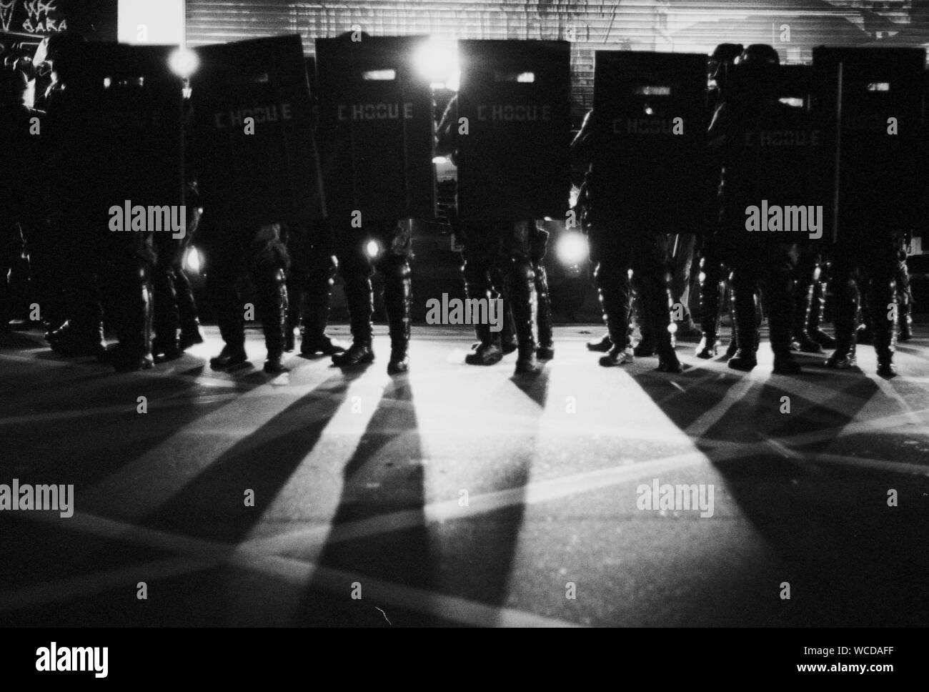Police Force Standing With Riot Shield On Illuminated Street Stock Photo