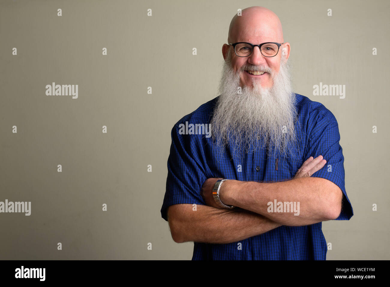Happy mature bearded bald man wearing eyeglasses with arms crossed ...