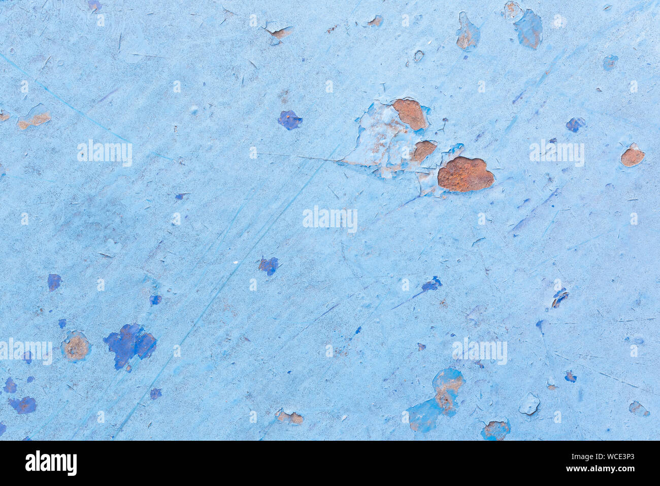 Close-up of a weathered and worn sheet metal plate painted in light blue. Paint is partly peeled off revealing rusty metal. Abstract background. Stock Photo