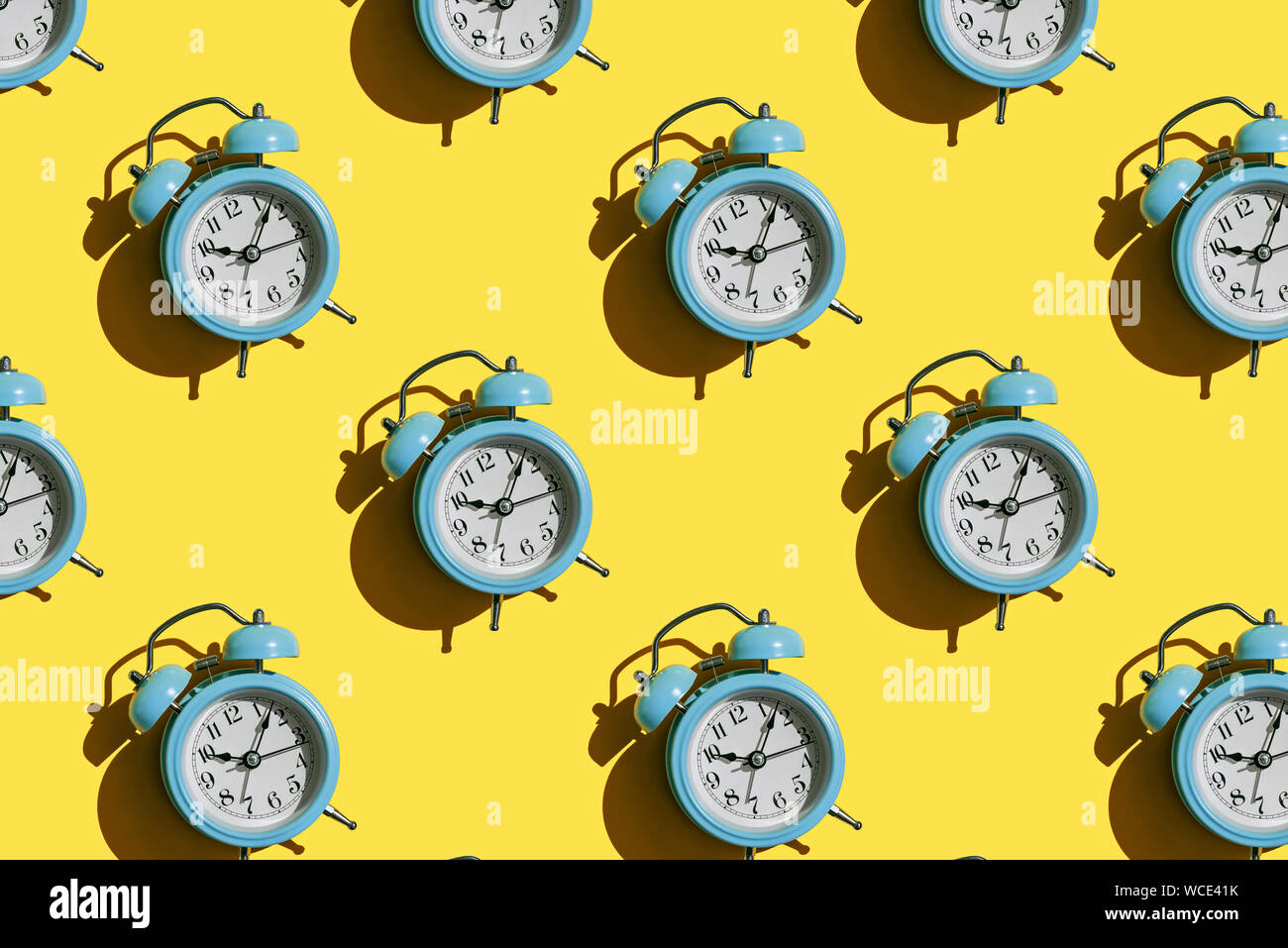 Blue alarm clock pattern on yellow background Stock Photo - Alamy