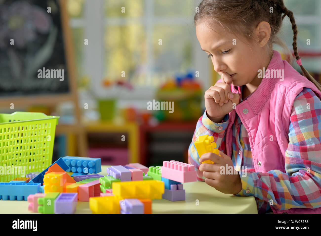 Little girl playing with colorful plastic blocks at home Stock Photo ...