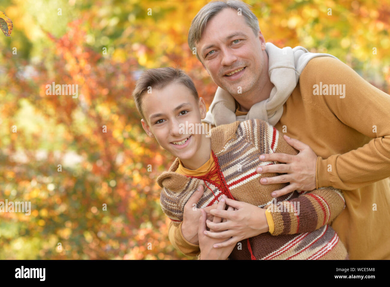 Smiling father and son hugging in autumn park Stock Photo - Alamy