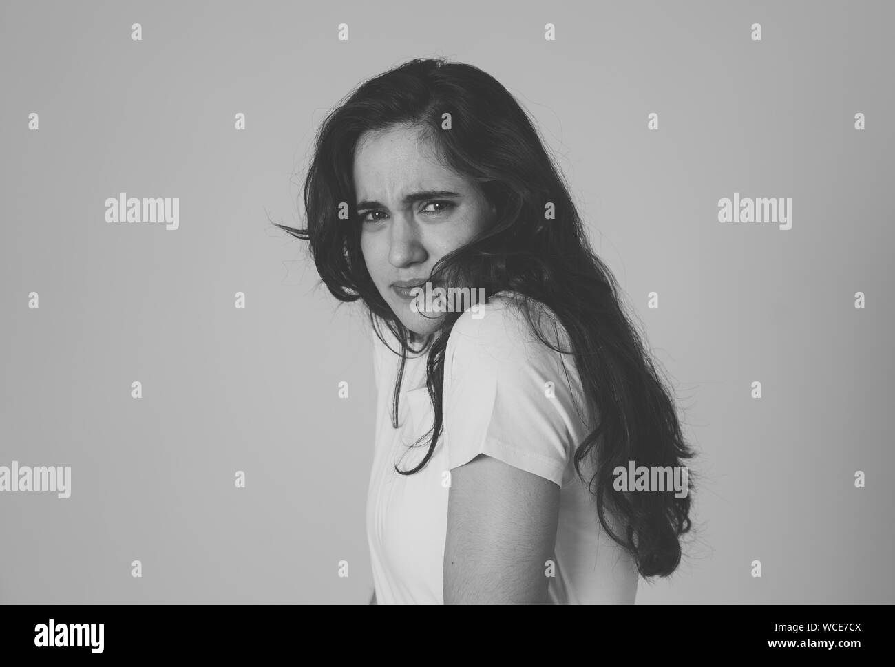 Portrait of young latin woman feeling scared and shocked making fear, anxiety gestures. Looking terrified covering herself. Copy space. In negative hu Stock Photo