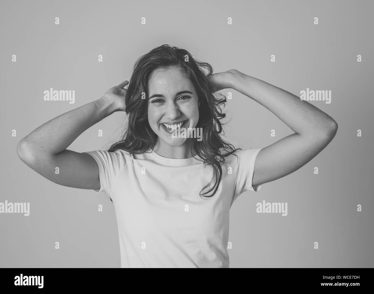 Young attractive latin woman celebrating success winning or feeling lucky and joyful dancing making celebration gestures with arms. Isolated on neutra Stock Photo