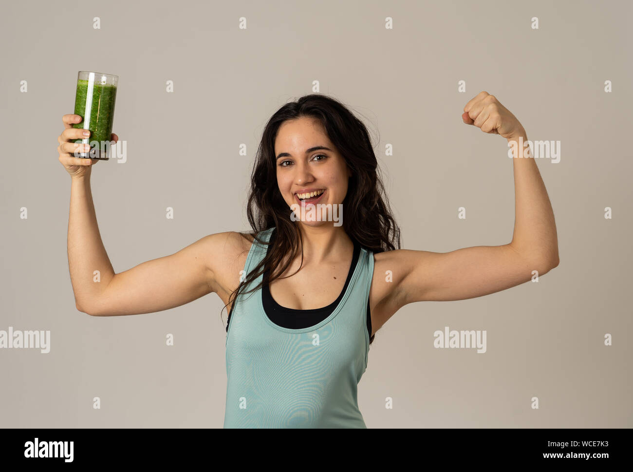 Fitness woman happy smiling holding glass of green vegetable smoothie posing happy and cute after training exercise felling fit and strong. In Body ca Stock Photo