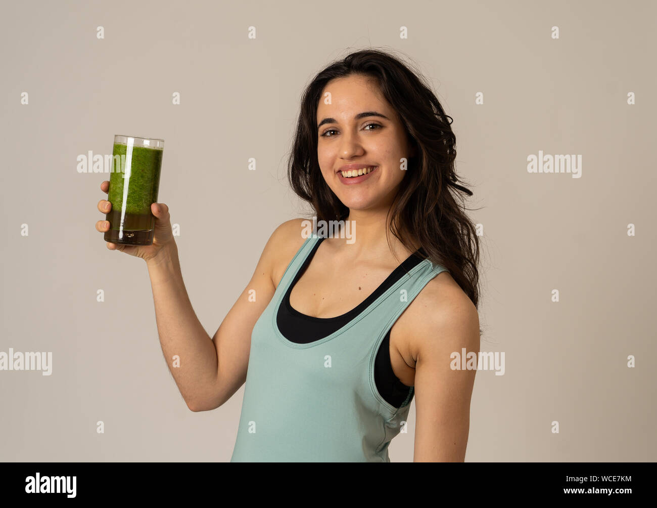 Fitness woman happy smiling holding glass of green vegetable smoothie after running or workout. Portrait isolated with copy space. Beauty Health Fitne Stock Photo