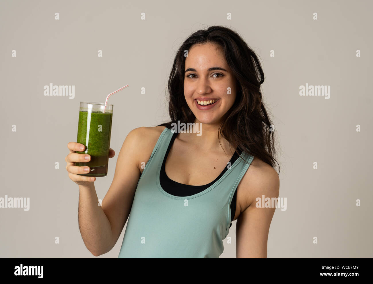 Fitness woman happy smiling holding glass of green vegetable smoothie after running or workout. Portrait isolated with copy space. Beauty Health Fitne Stock Photo