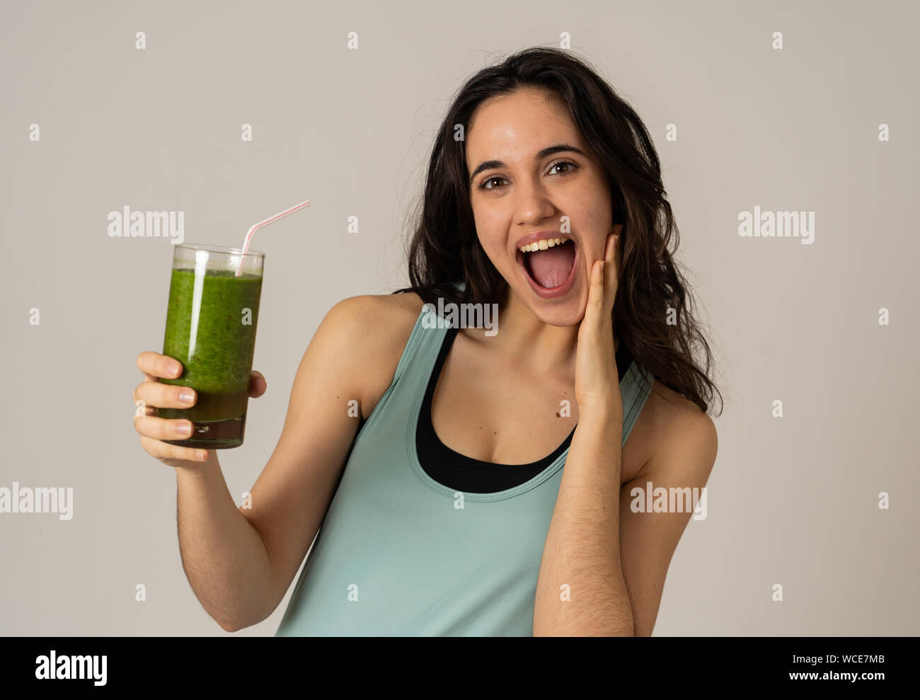 Fitness woman happy smiling holding glass of green vegetable smoothie after running or workout. Portrait isolated with copy space. Beauty Health Fitne Stock Photo