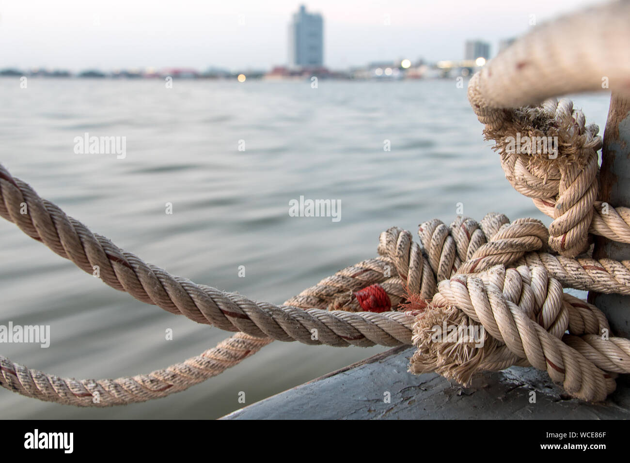 Boat rope tied to a wooden post on a floating boat railing, close