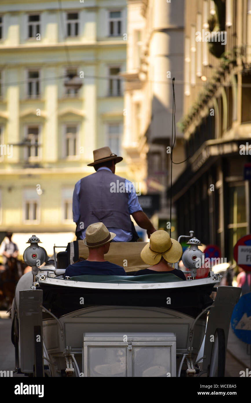 A horse carriage with tourists drives through the streets of downtown Vienna. Austria Stock Photo