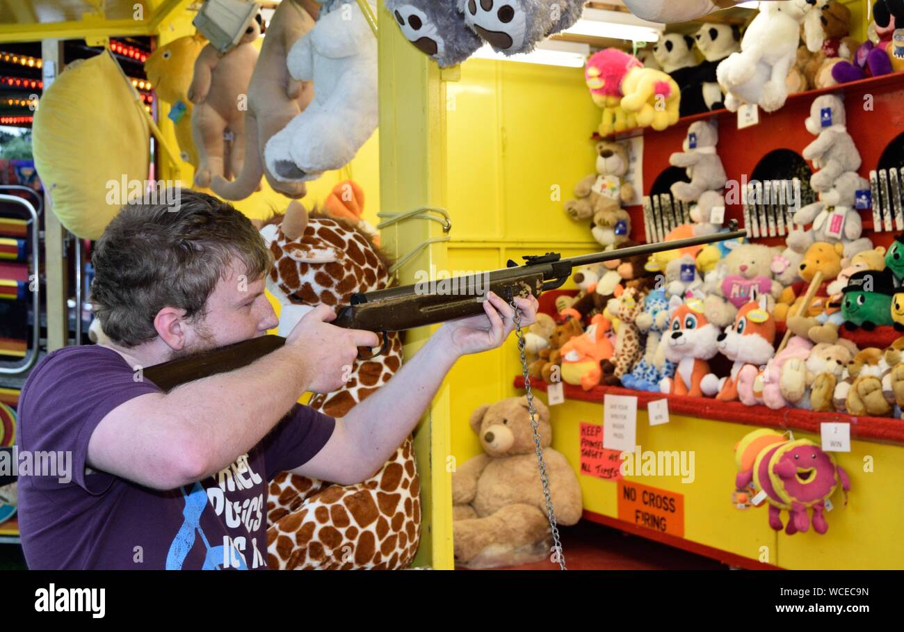 Young male adult firing an air rifle at a fairground shooting gallery Stock Photo