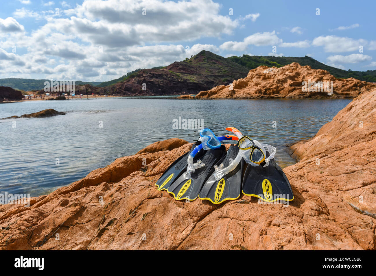 MENORCA, SPAIN - SEPTEMBER 25, 2017: snorkeling equipment of CRESSI brand on red ochre rocks of the beach 'cala pregonda' in Menorca. Stock Photo