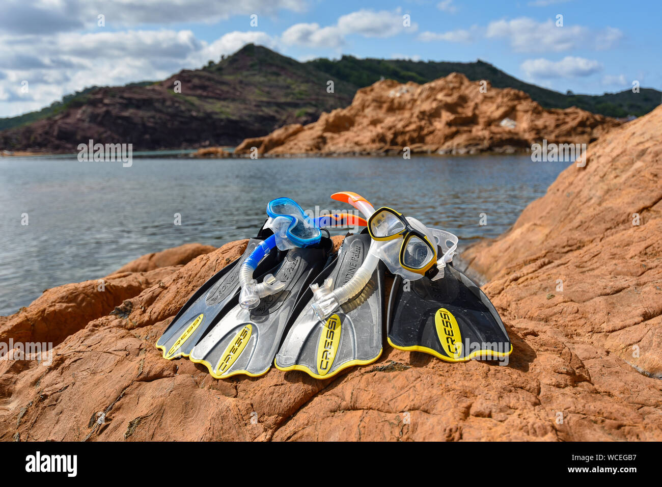 MENORCA, SPAIN - SEPTEMBER 25, 2017: snorkeling equipment of CRESSI brand on red ochre rocks of the beach 'cala pregonda' in Menorca. Stock Photo
