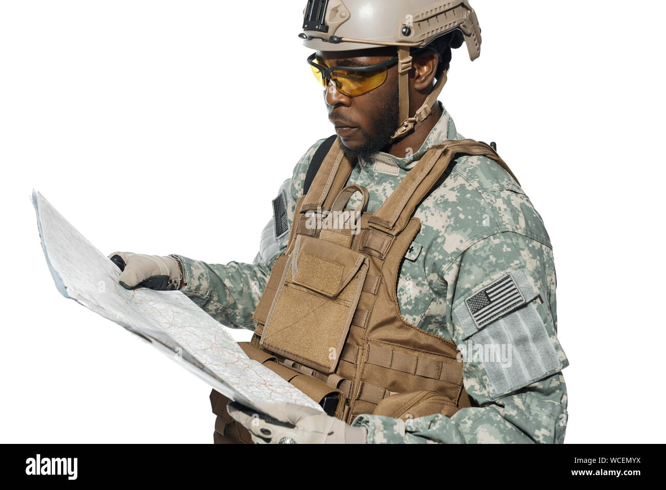 American soldier wearing uniform and helmet holding map and looking at locality objects. African male soldier in armour navigating with map. Concept of army. Stock Photo