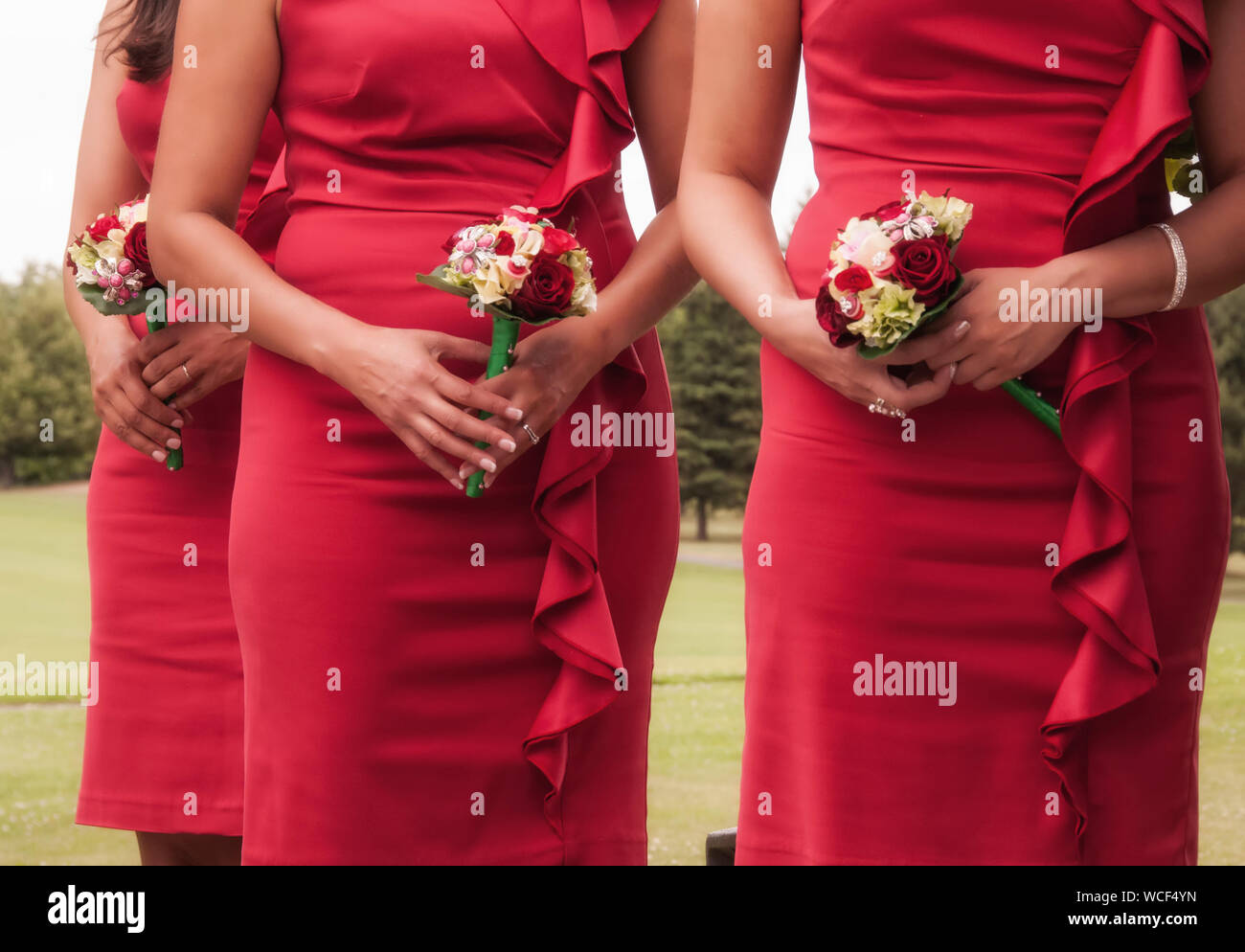 Midsection Of Bridesmaids Holding Bouquets In Lawn Stock Photo
