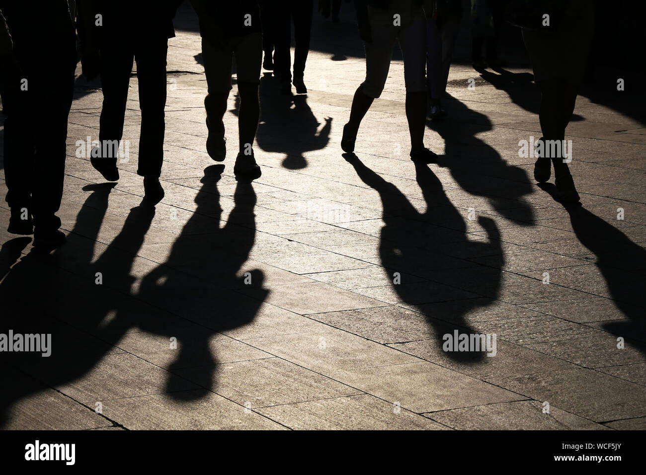 Black silhouettes and shadows of people on the street. Crowd walking down on sidewalk, concept of pedestrians, crime, society, city life Stock Photo