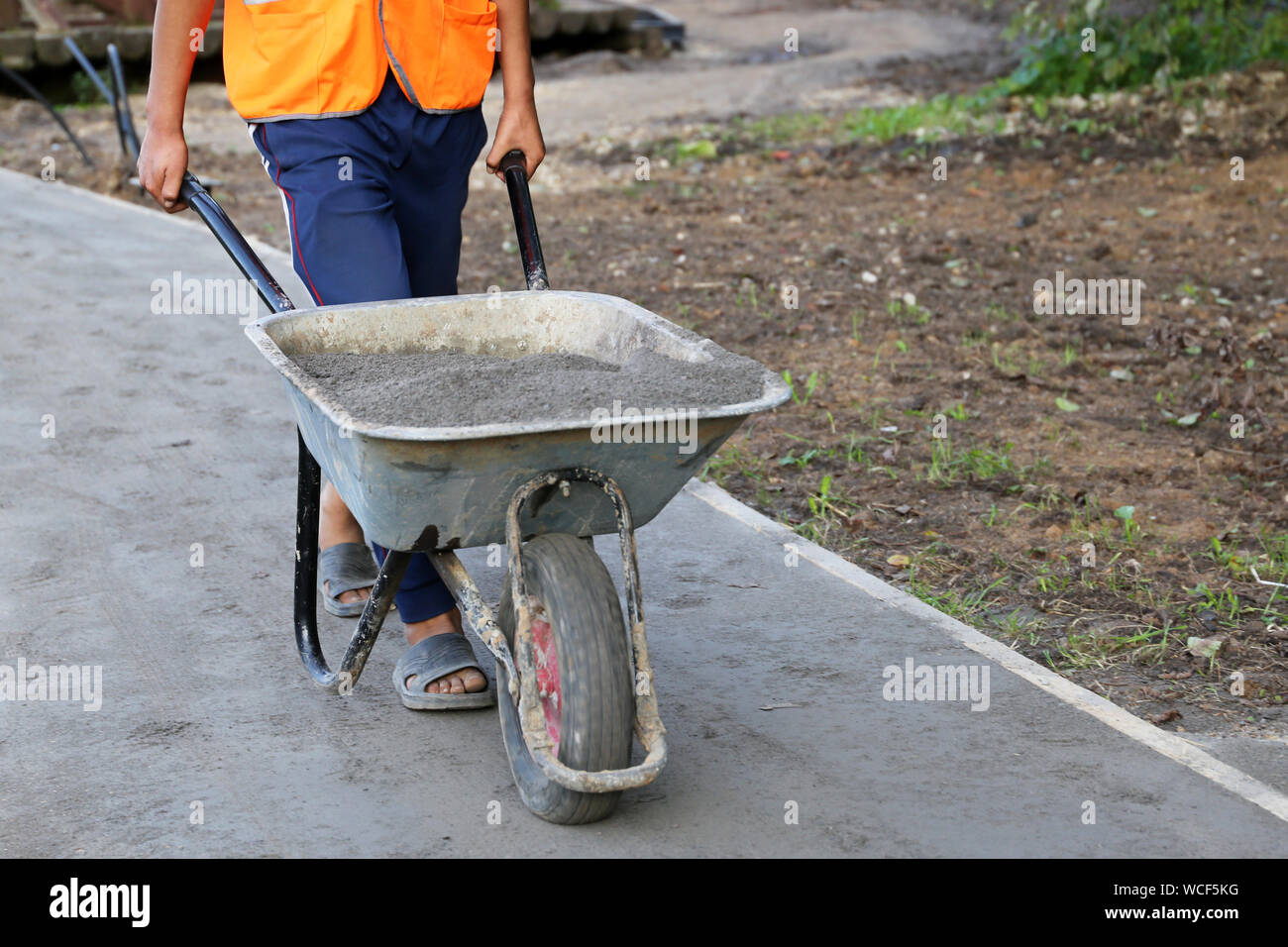 Worker carries a wheelbarrow with the ground. Man with cargo, concept of earthworks, digging, construction of the road, landscaping Stock Photo