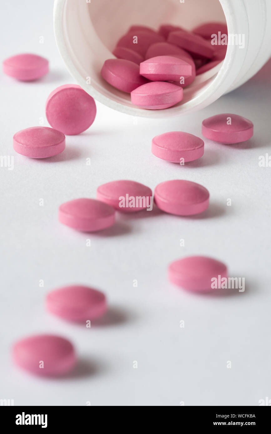 Close-up Of Pink Pills Spilling From Plastic Bottle Stock Photo