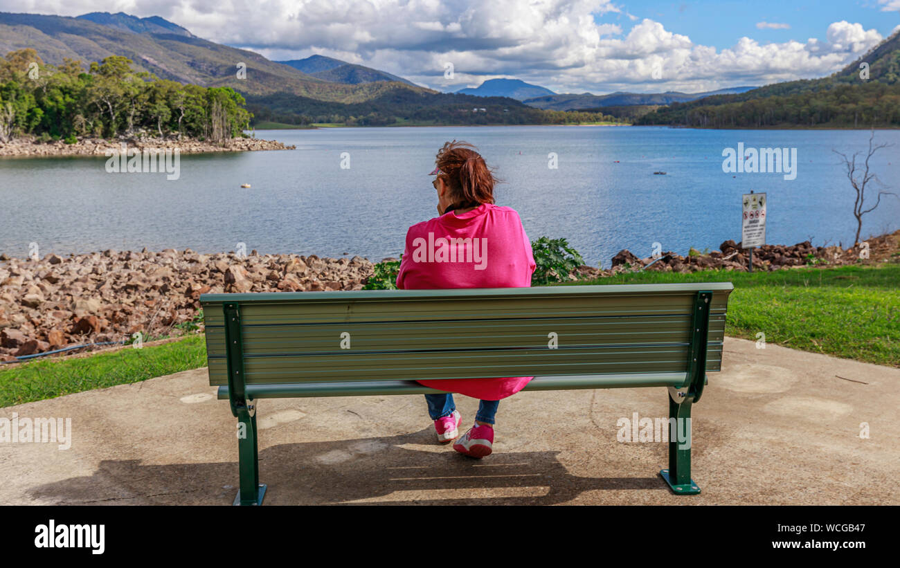 Lady on bench looking across water Stock Photo