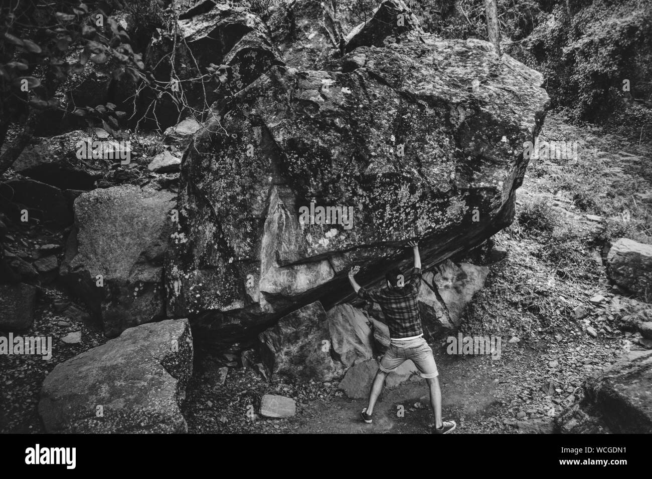 Optical Illusion Of Man Pushing Boulder Rock Stock Photo