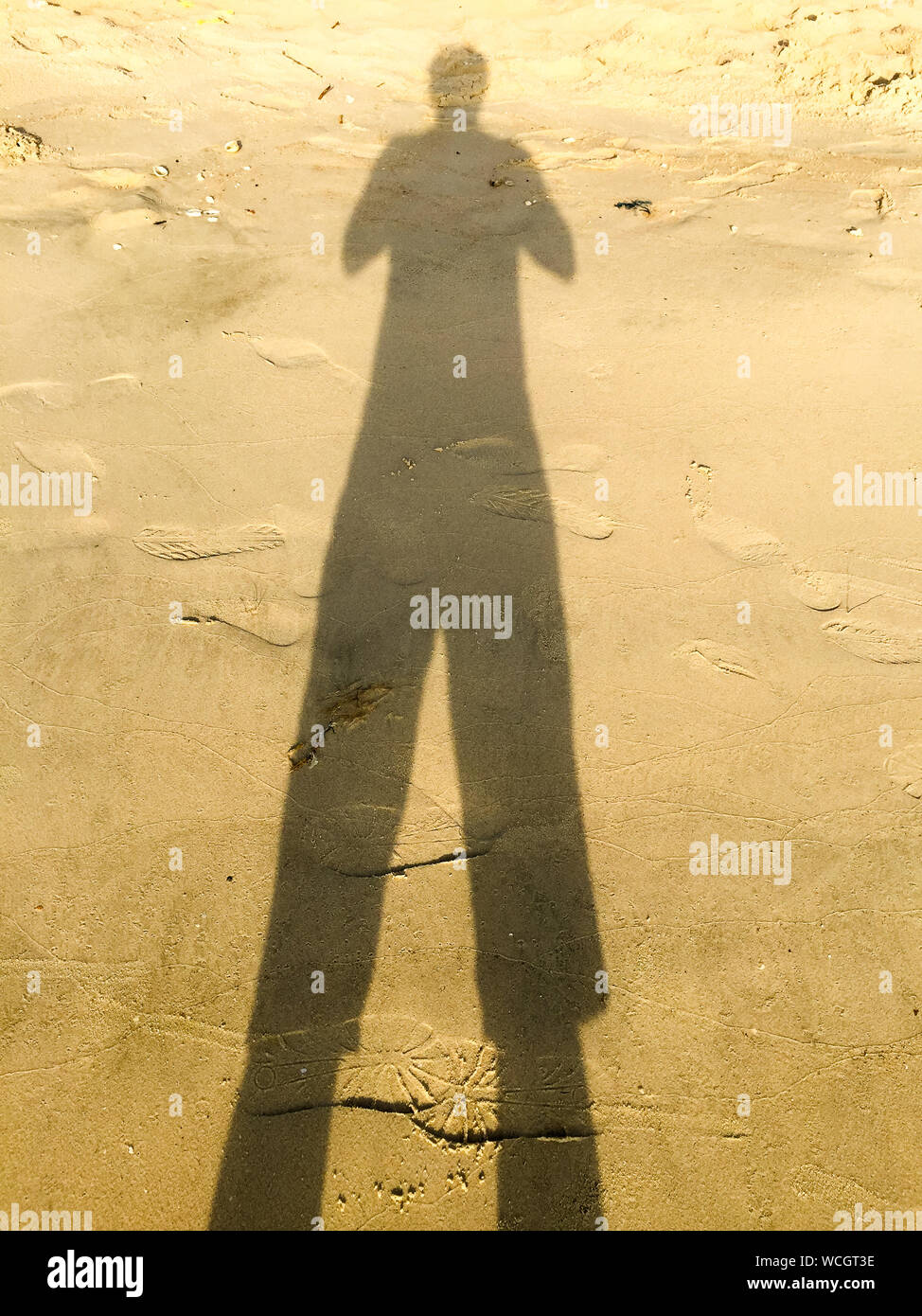 Shadow Of Person Falling On Sand At Beach During Sunny Day Stock Photo