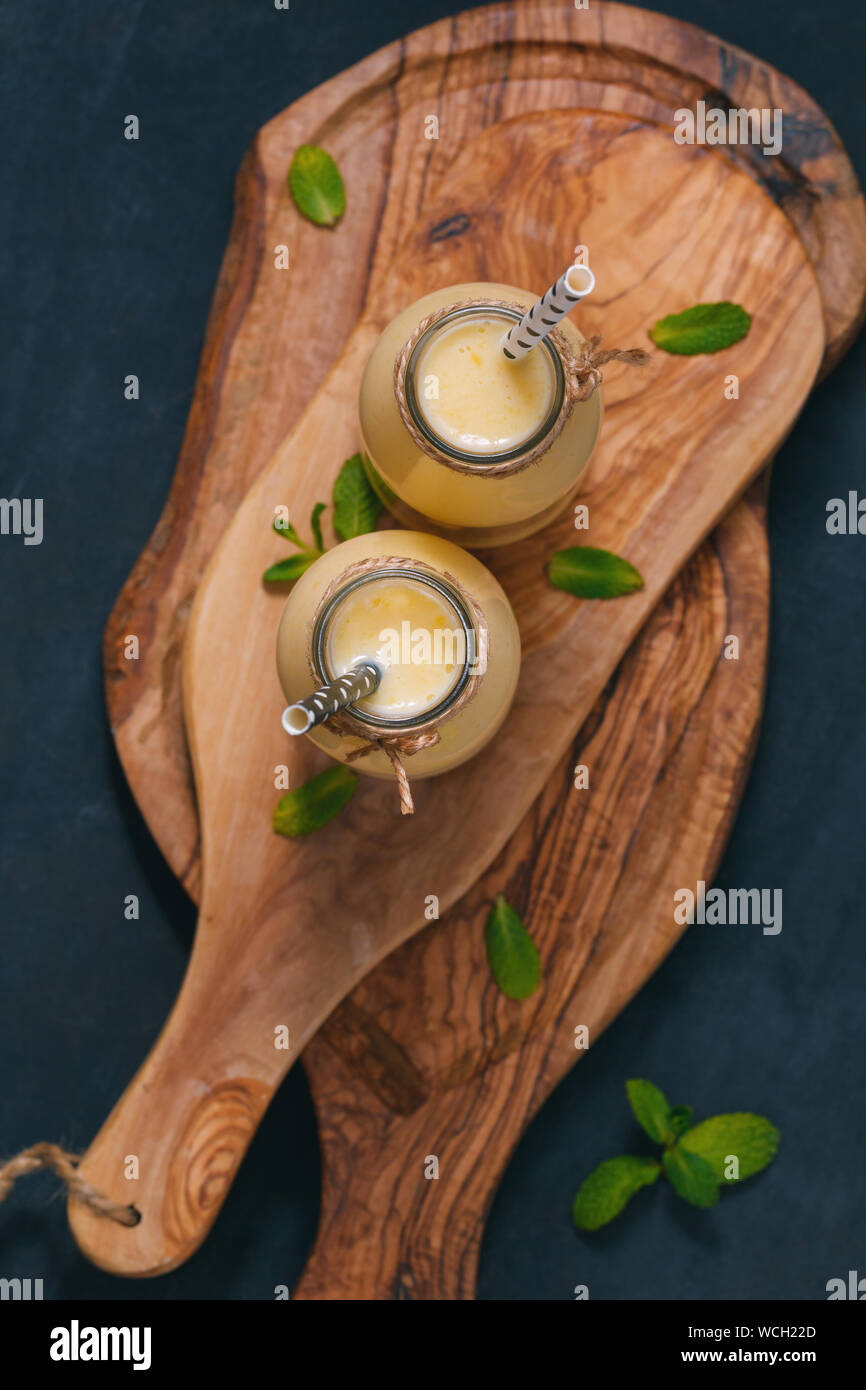 The Yellow Fruit Smoothie In The Glass Bottles With Straw On The