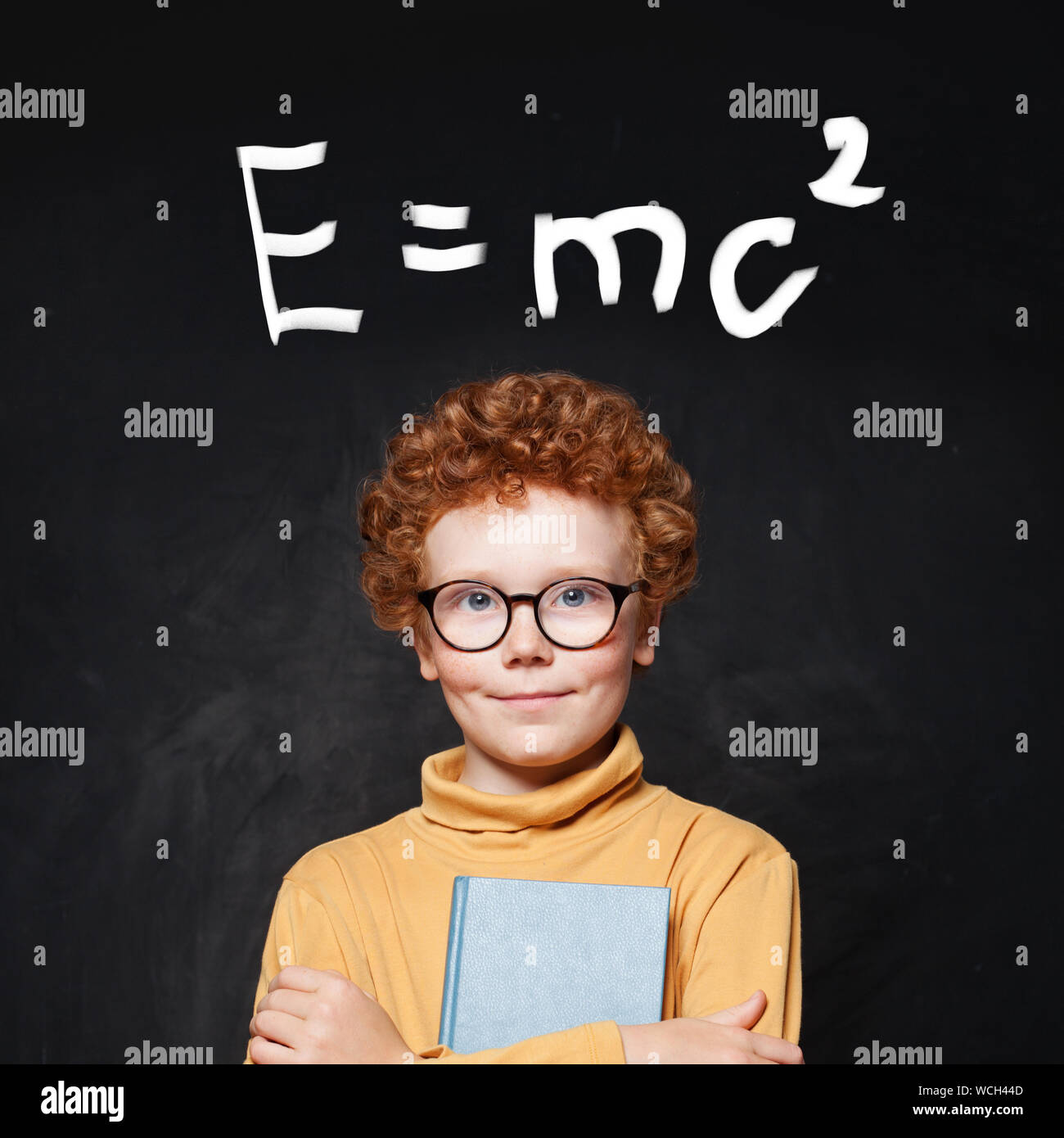 Happy young boy genius and science formula against chalkboard Stock