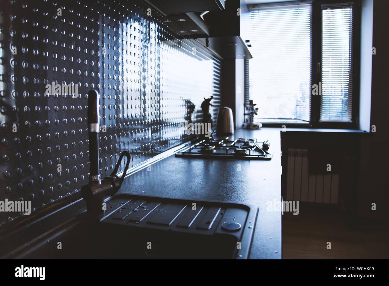 Black gas stove and sink in kitchen with black interior Stock Photo - Alamy