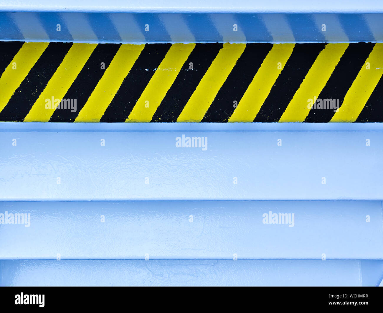 Black and yellow diagonal stripes sign on back side of metal staircase ...