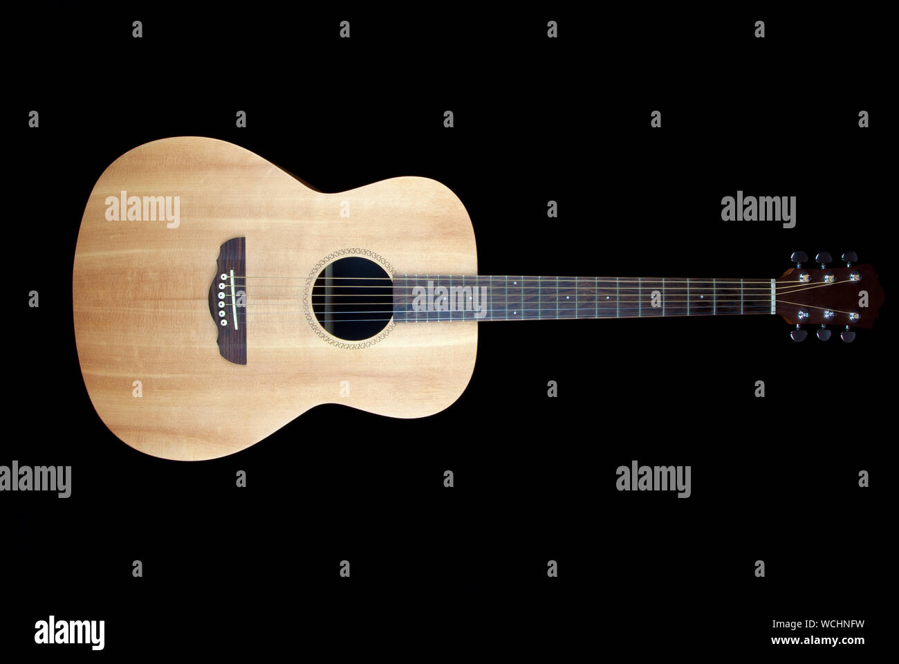Acoustic folk guitar against black background. Stock Photo