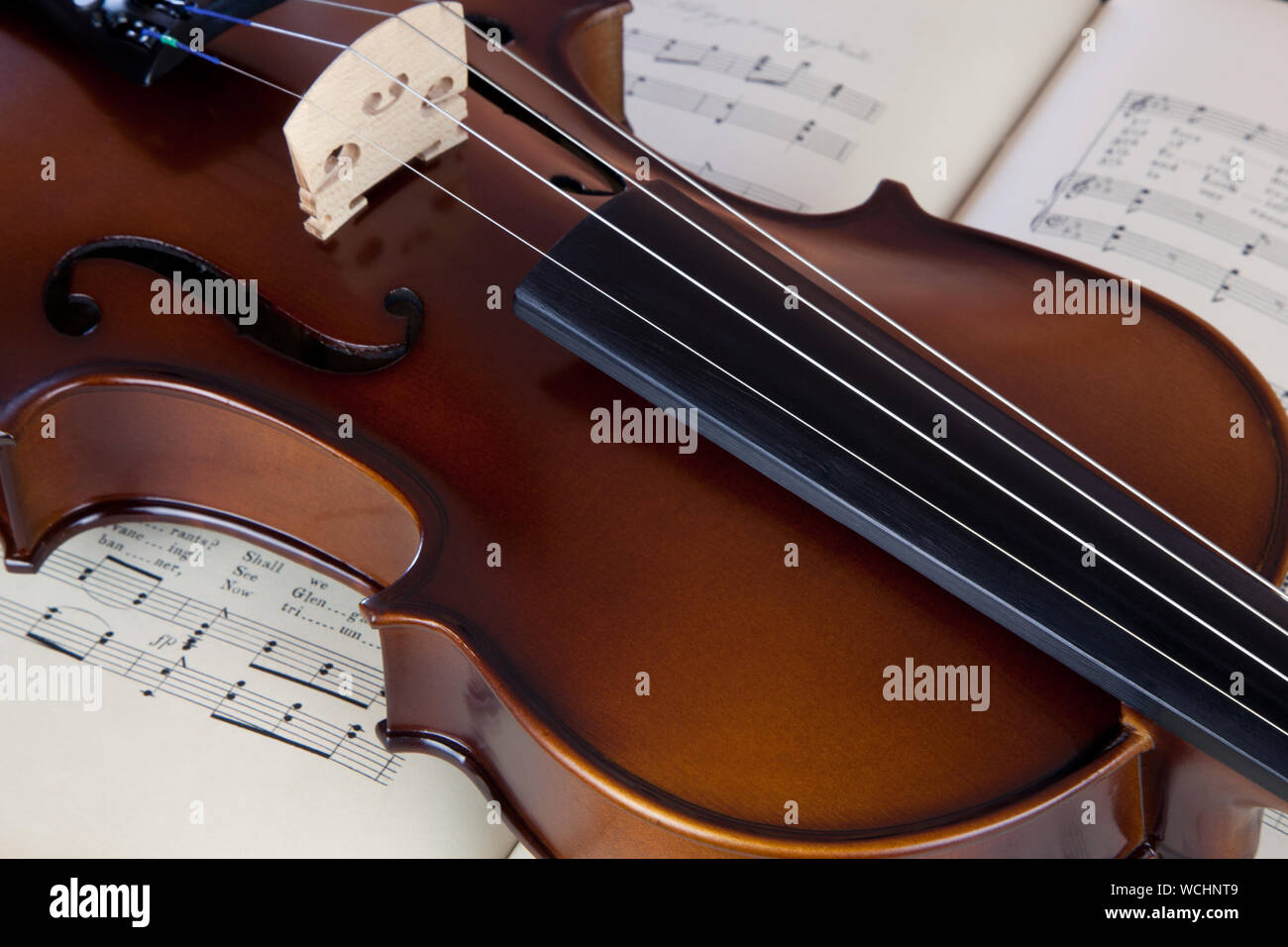 Classical violin resting upon an open old sheet music book of scottish folk songs. Stock Photo