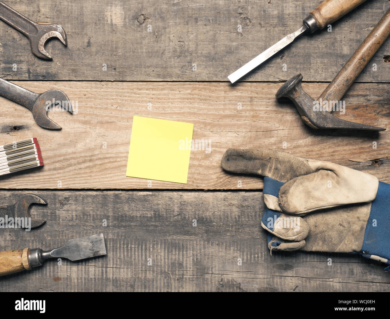 Old used tools with a sticky note on a workbench with space for text Stock Photo