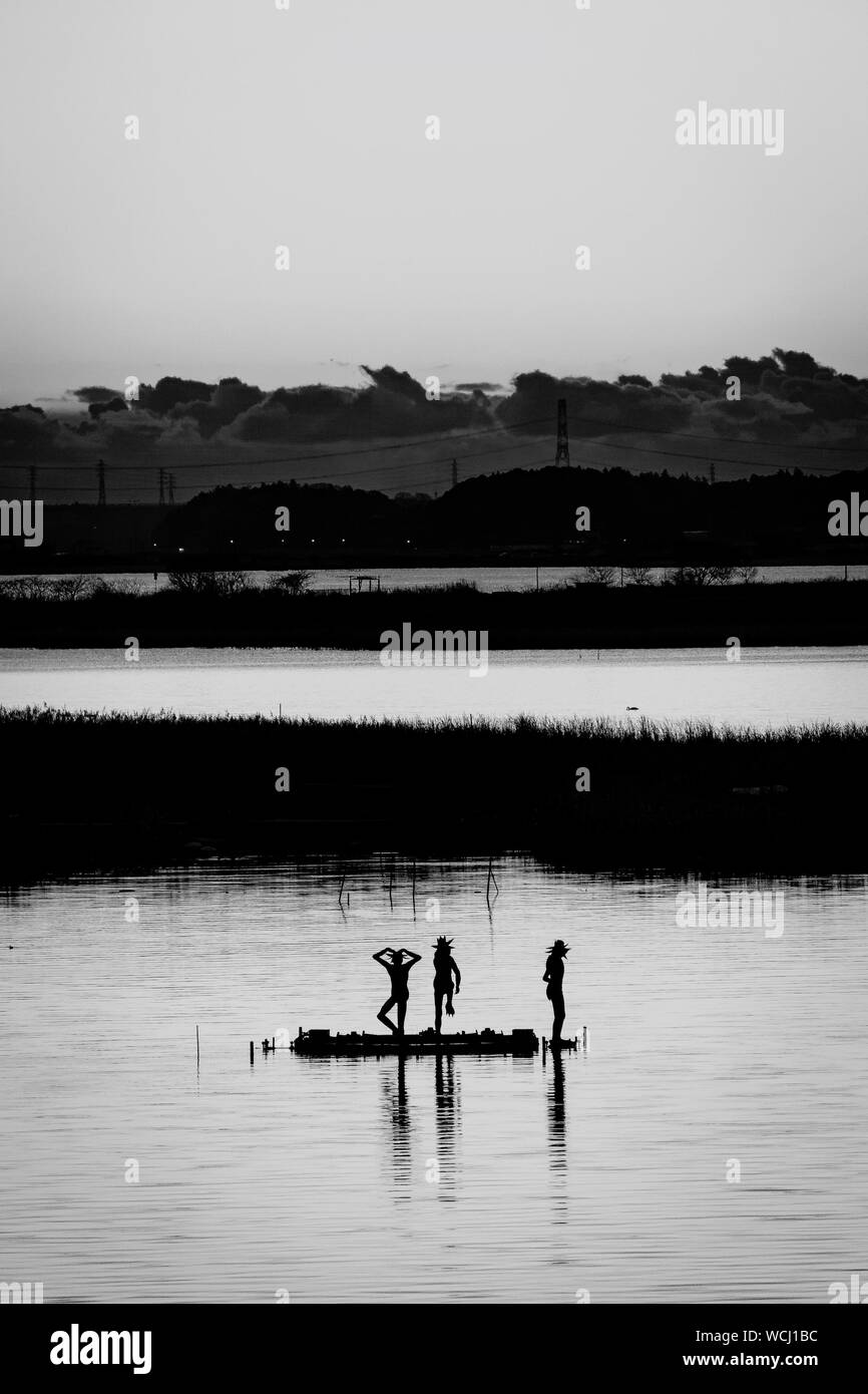 Silhouette People Posing In Lake Against Sky Stock Photo