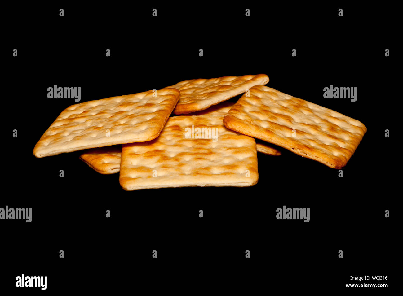 Stack of crispy crackers isolated against a black background. Stock Photo