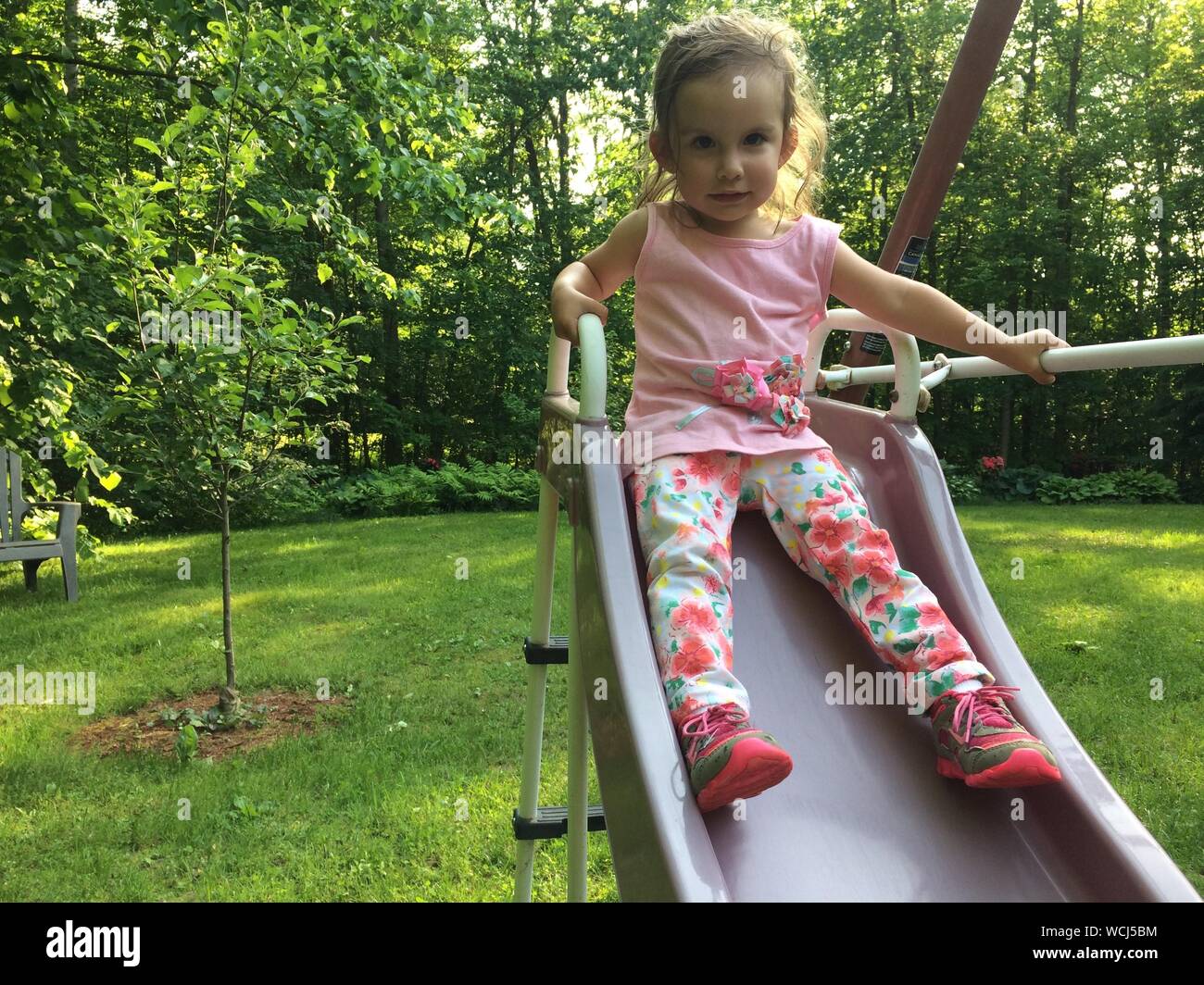 Portrait Of Girl Sitting On Slide In Playground Stock Photo - Alamy