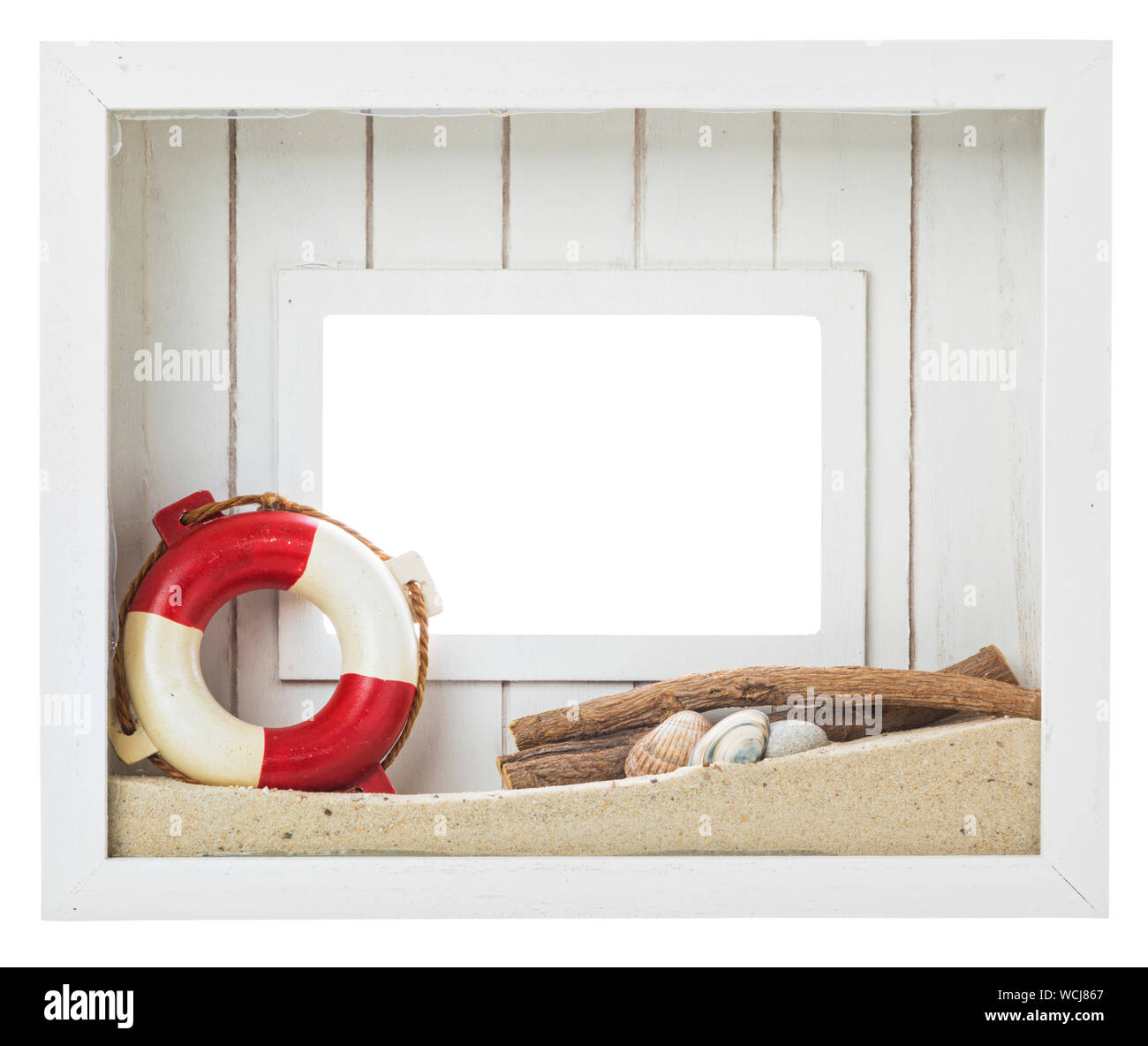 Rustic white picture frame decorated with sand, sea shells, driftwood and life belt. Isolated with clipping path on white background. Stock Photo