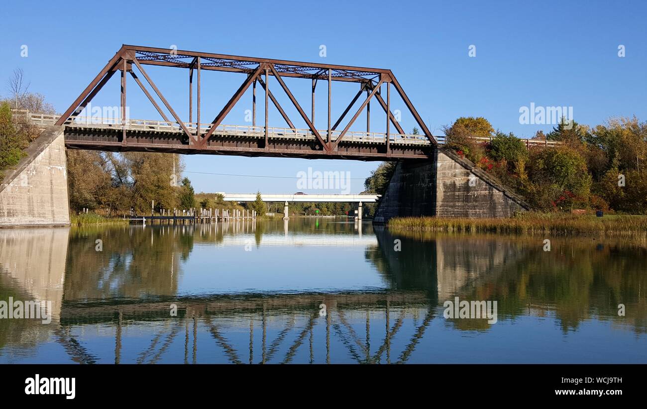 Railway Bridge Over River With Reflection Against Clear Sky Stock Photo