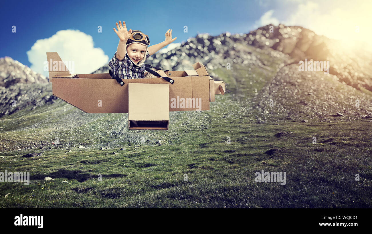 Portrait Of Boy Sitting In Toy Plane Over Hill Stock Photo