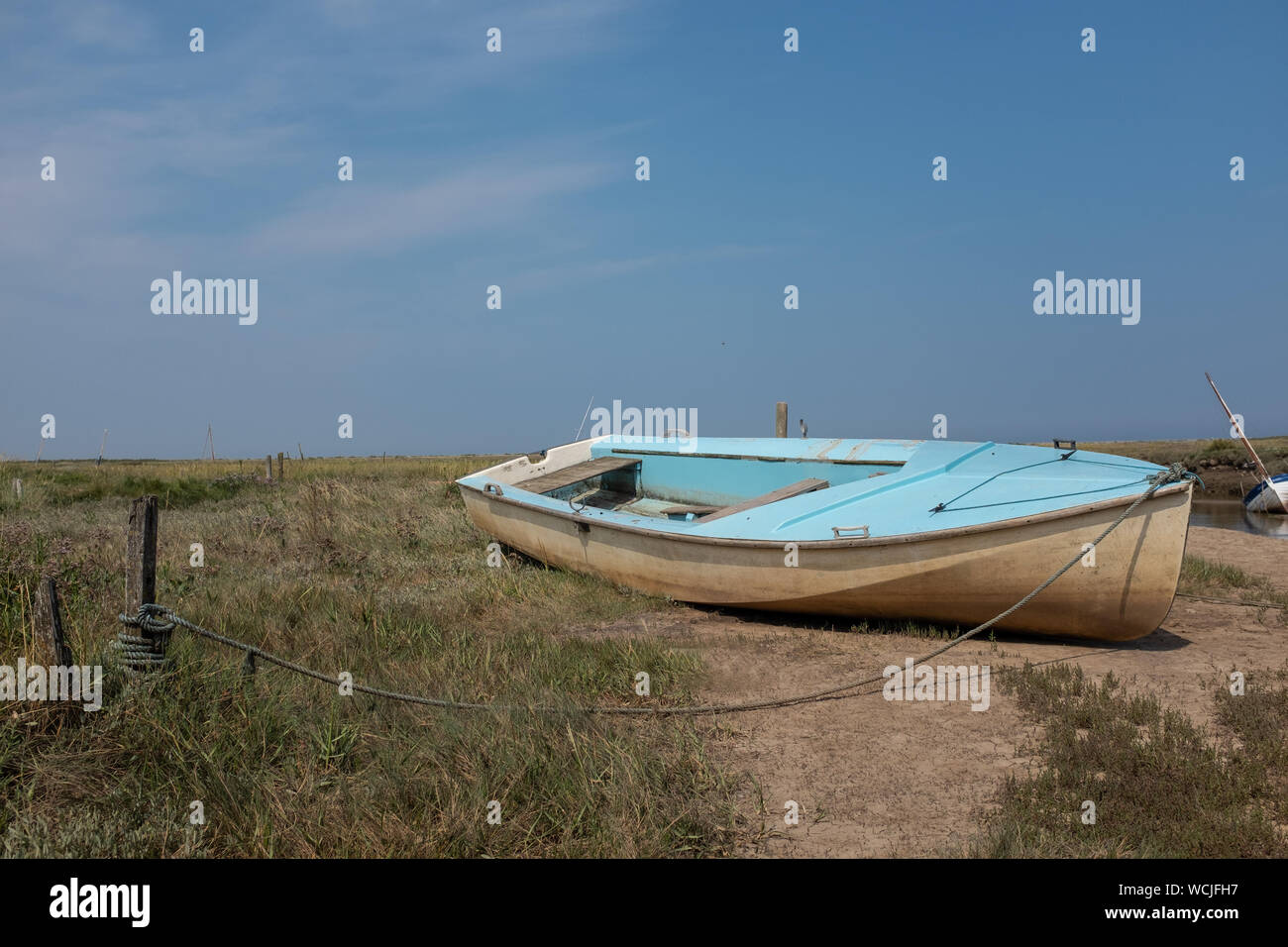 Little blue boat moored next to River Glaven at Blakeney, Norfolk, UK Stock Photo