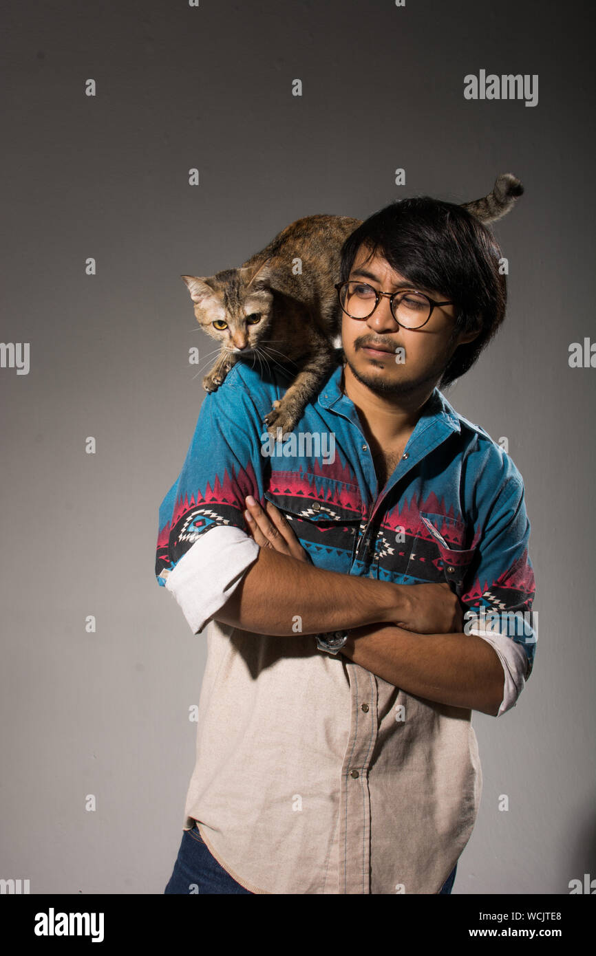 Young Man With Cat On His Shoulder Against Gray Background Stock Photo -  Alamy