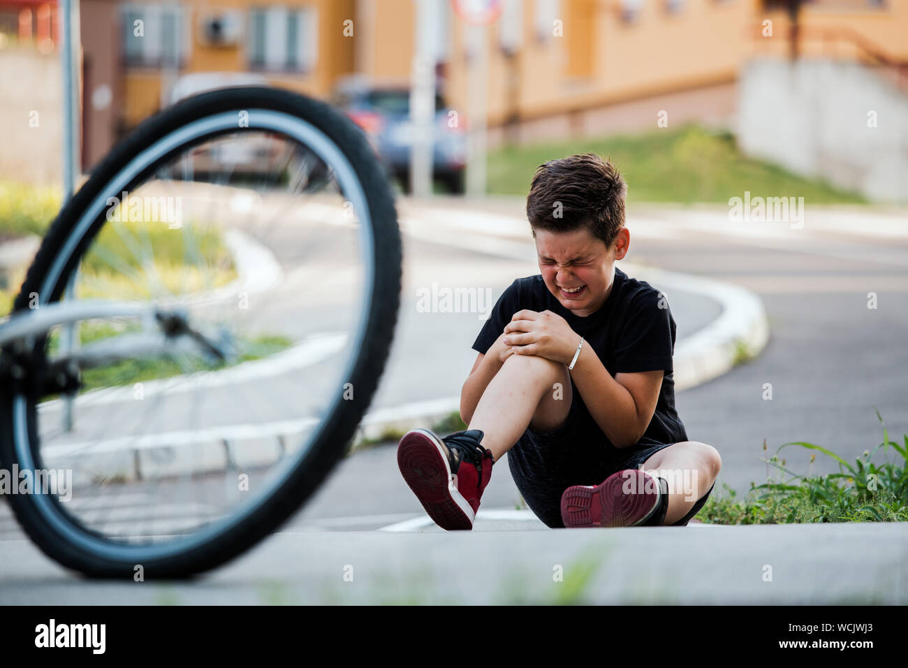 Teenage boy There is a knee injury, as the bike falls while riding. Kid hurt his leg after
